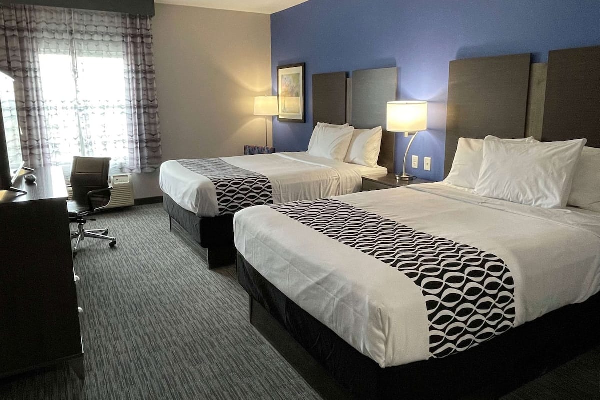 Ein Hotelzimmer mit zwei Betten, einem Schreibtisch und einem Stuhl.