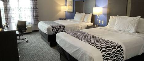 A hotel room with two beds, a desk, and a chair.