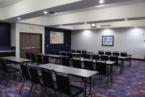 A conference room with tables and chairs, an exit sign, a door, and a wall with a framed picture. -  La Quinta Inn and Suites by Wyndham Schertz-San Antonio-Selma (Schertz)