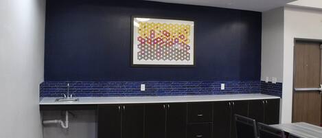 A kitchen with a blue backsplash, a colorful abstract art piece, and a patterned floor.