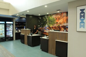 A reception area with a counter, a digital kiosk, and a refrigerator stocked with beverages. -  La Quinta Inn and Suites by Wyndham Schertz-San Antonio-Selma (Schertz)
