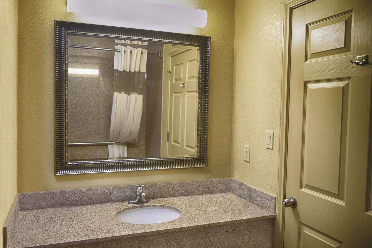 A bathroom with a granite countertop sink, a mirror, and a door.