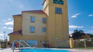 A hotel with a swimming pool, a sign reading "La Quinta Inn & Suites", and a fenced outdoor area. - La Quinta Inn & Suites by Wyndham Alice (Alice)