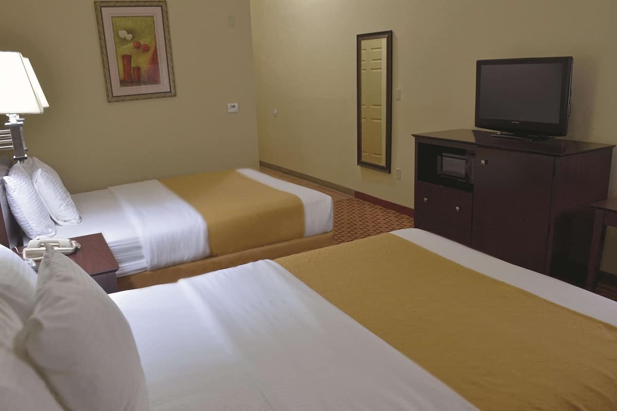 A hotel room with two beds, a television, a desk, and a telephone.