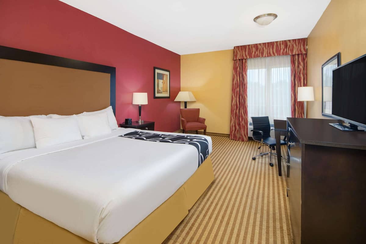 Habitación de hotel con una cama grande, un escritorio con computadora, una silla y un televisor.