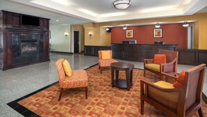 Un hall con chimenea, zona de estar y mostrador de recepción.