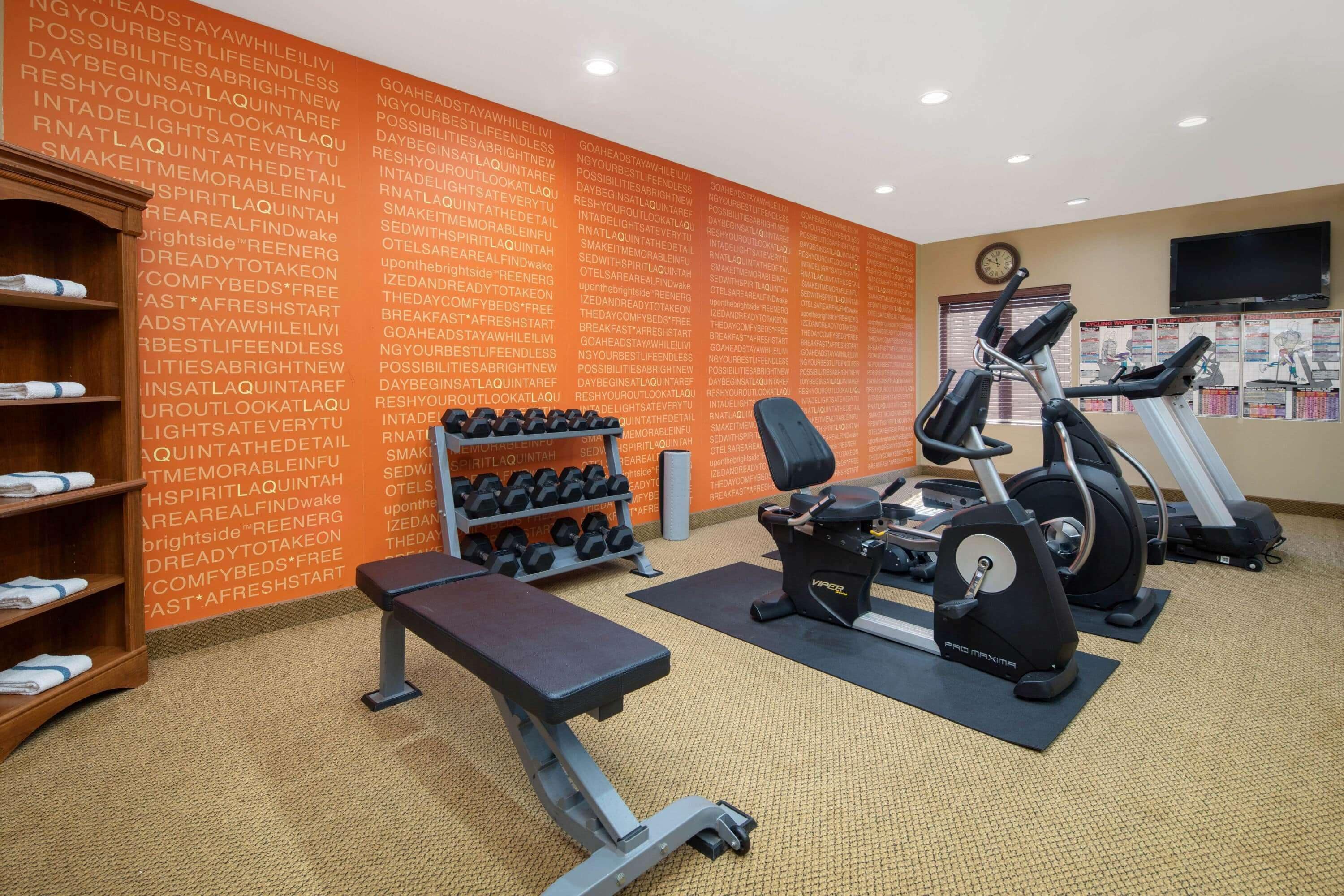 A gym with treadmills, a stationary bike, and dumbbells.