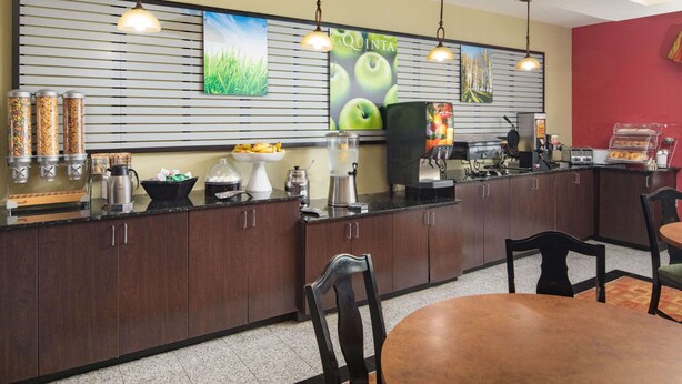 Una cocina de hotel con mostrador, máquinas de café y un cartel grande en la pared.