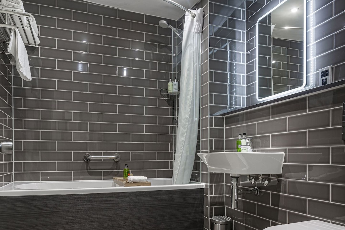 A modern bathroom with a bathtub, shower, and toilet.