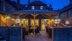 An outdoor patio area with tables and chairs, a covered seating area, and brick walls. - The Kings Arms and Royal Hotel, Godalming, Surrey (Godalming)