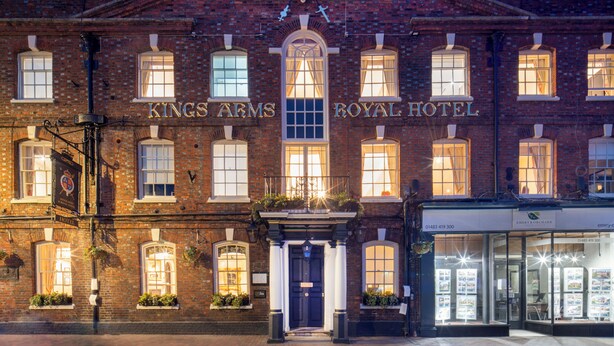 A historic building with 'Kings Arms Royal Hotel' signage, featuring a prominent entrance, brick facade, and a traditional emblem above the entrance. - The Kings Arms and Royal Hotel, Godalming, Surrey (Godalming)