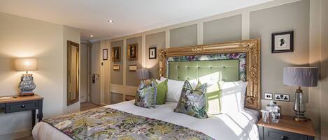 Habitación de hotel con una cama grande, una mesita de noche, una lámpara y cuadros en las paredes.