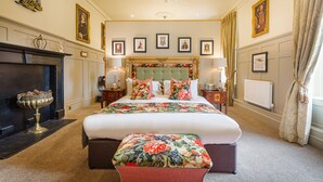 A large bed with a floral bedspread, a chandelier, framed pictures on the wall, and a fireplace. - The Kings Arms and Royal Hotel, Godalming, Surrey (Godalming)