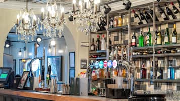 Una zona de bar con una estantería de vinos y licores, una caja registradora y una barra.