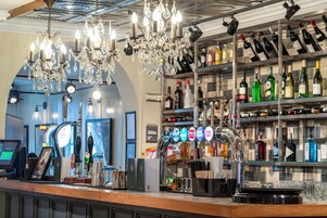 Una zona de bar con una estantería de vinos y licores, una caja registradora y una barra.