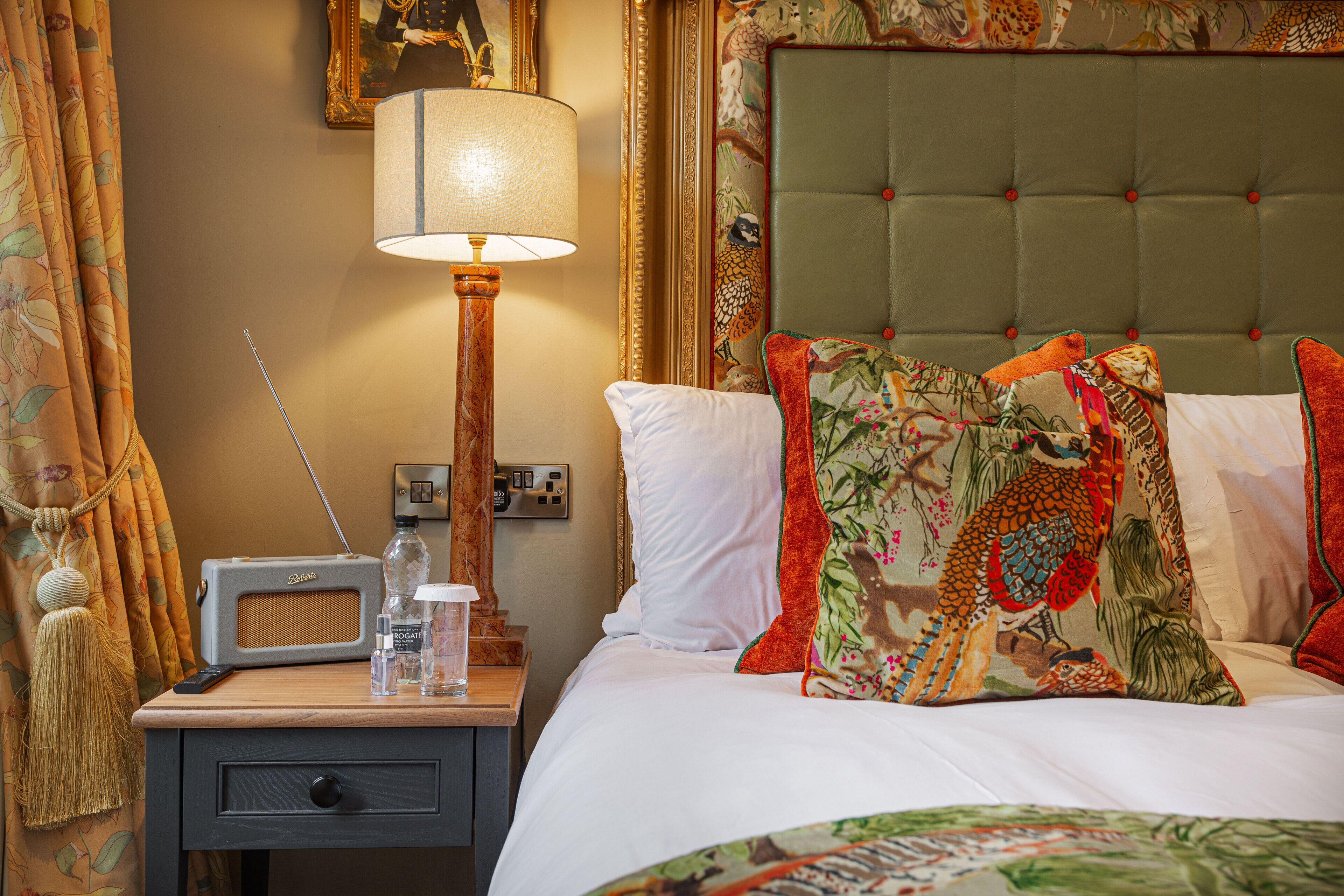 A hotel room with a bed, a nightstand with a lamp, a radio, and a telephone.