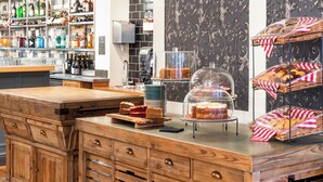 A bakery counter with cakes and pastries, a wine and liquor display, and a patterned wall. - The Kings Arms and Royal Hotel, Godalming, Surrey (Godalming)