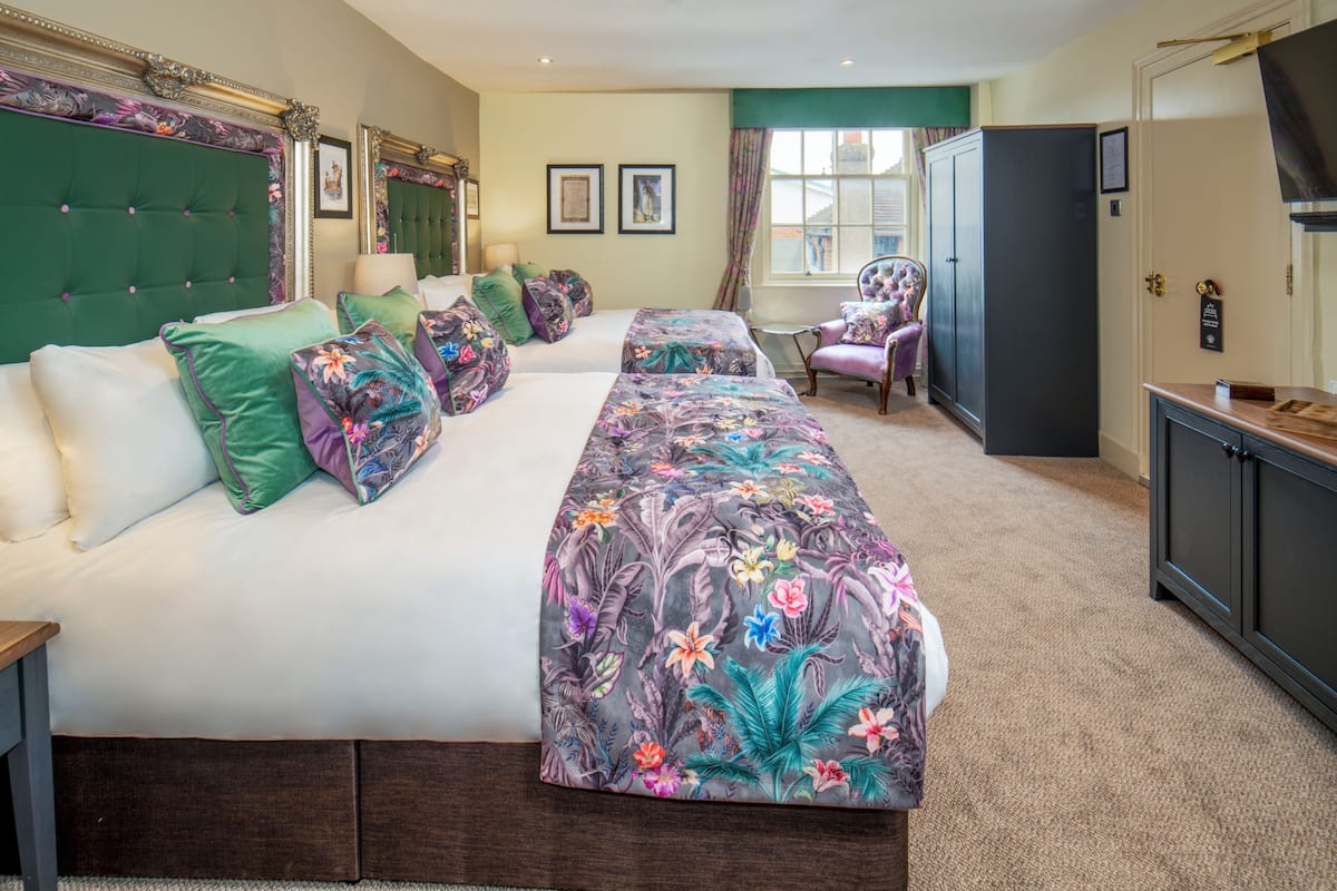 A hotel room with a large bed, a chair, a wardrobe, and a window.