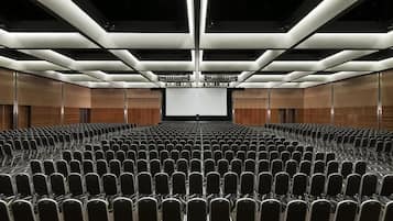 A conference room with rows of chairs, a large screen at the front, and a modern ceiling design.