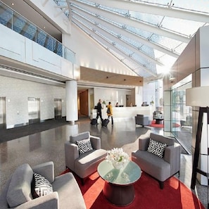 A spacious lobby with a high ceiling, glass railings, and a central seating area with sofas and a coffee table. - Crown Promenade Perth (Perth)