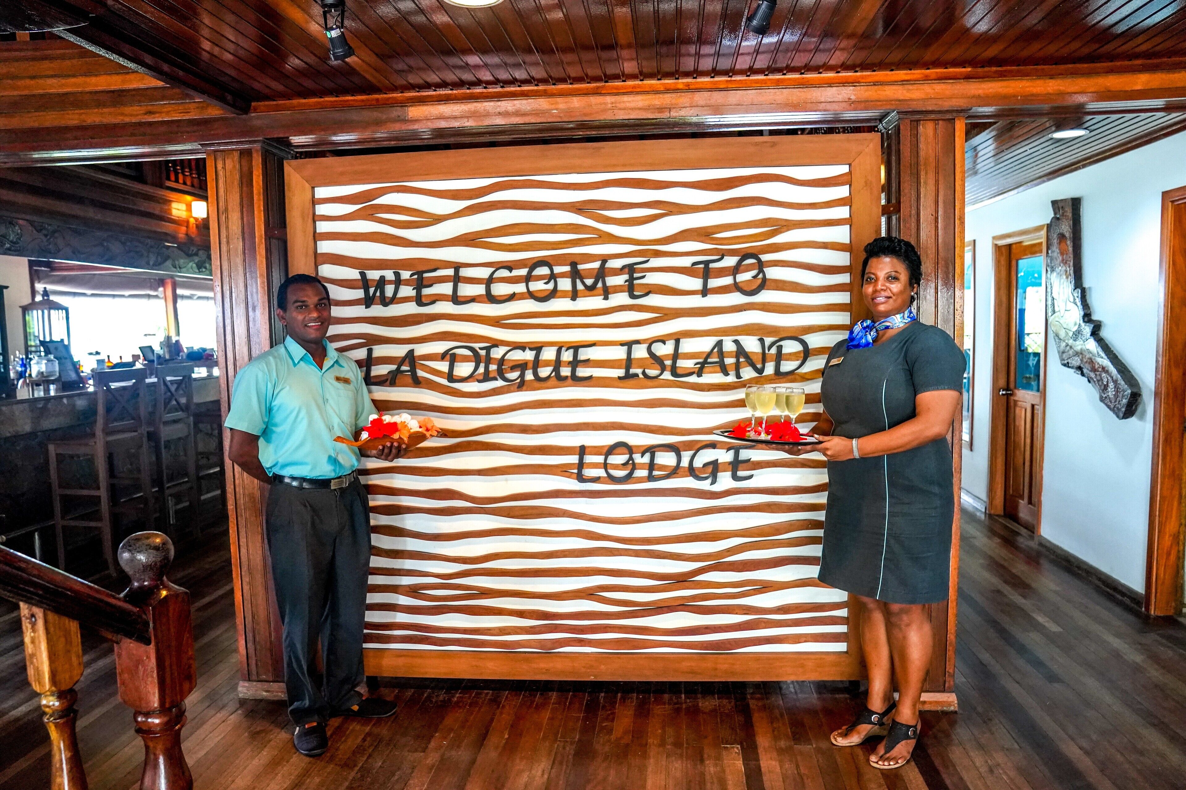 A wooden interior with a welcome sign for La Digue Island Lodge.