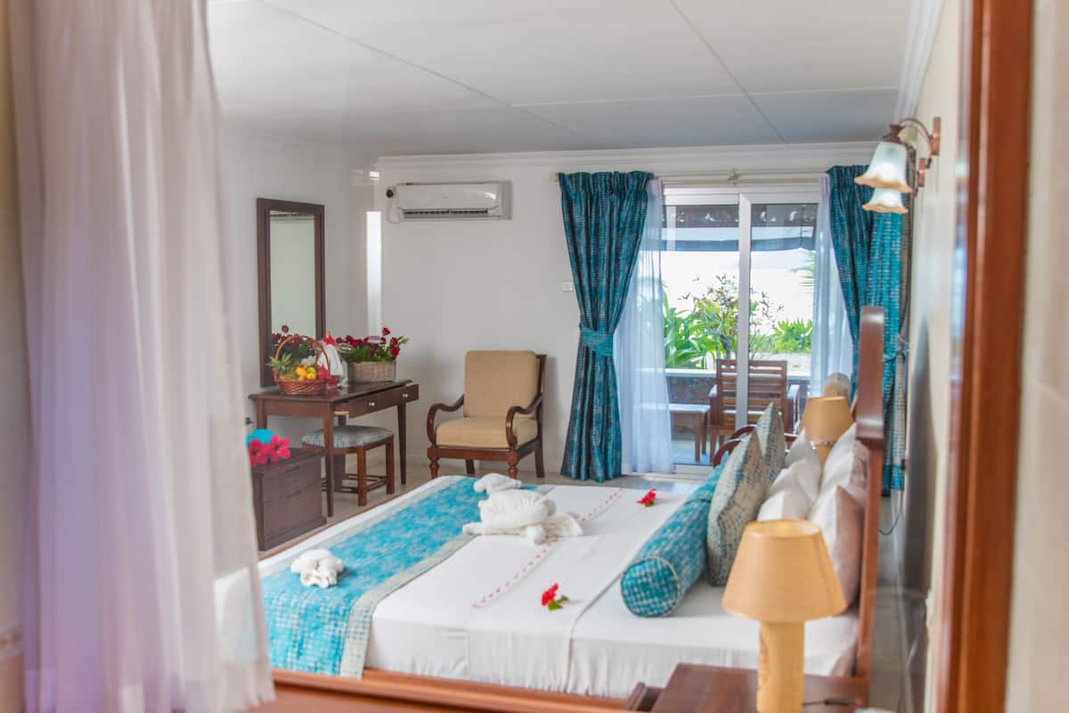 Habitación de hotel con una cama, un escritorio de madera, una silla, un espejo y vistas al exterior.