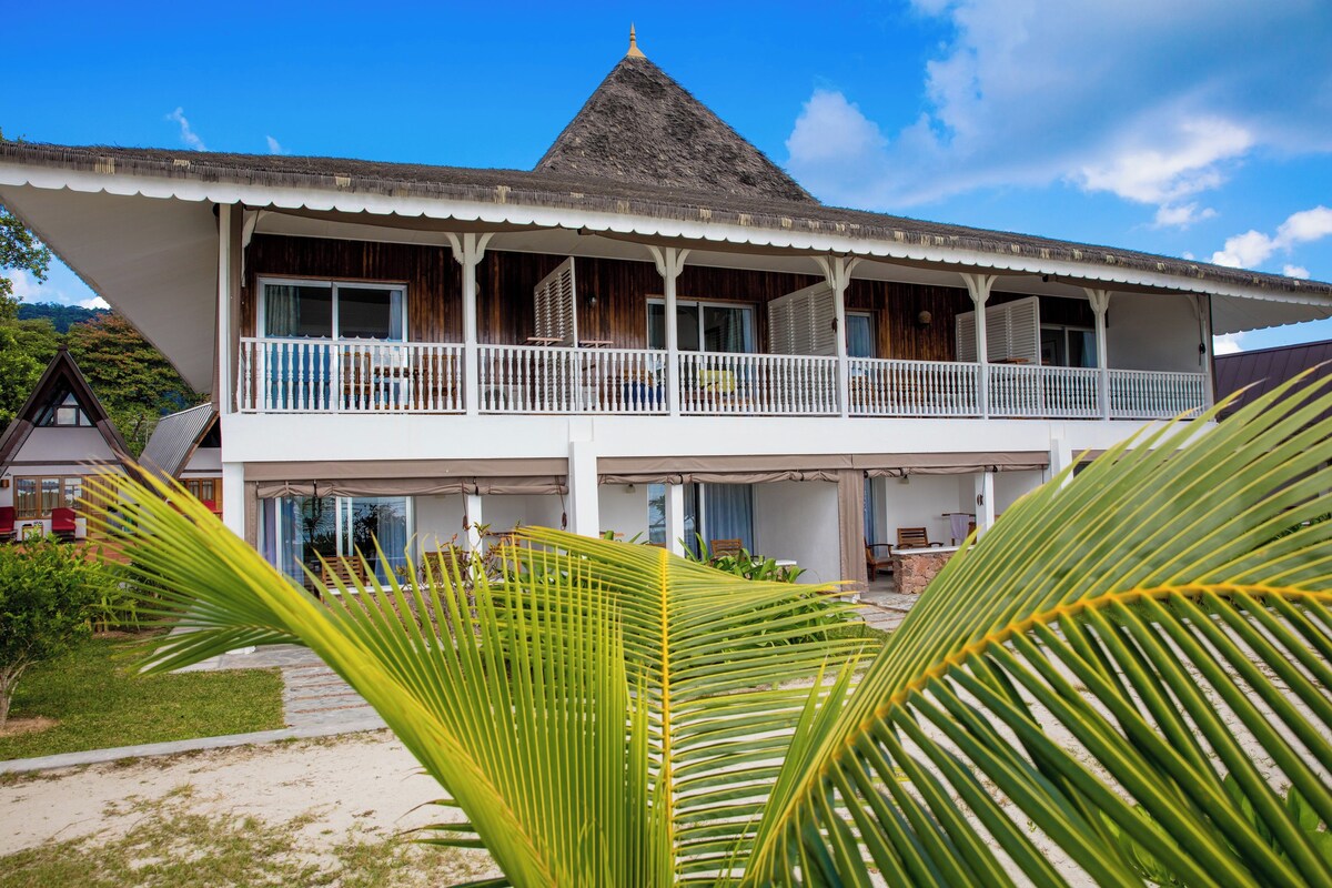 A two-story building with a balcony, a thatched roof, and a view of the surrounding landscape.