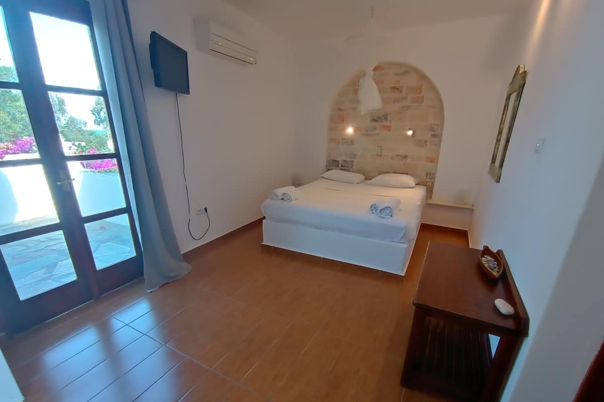 Un dormitorio con cama, televisor montado en la pared y una mesita con un cuenco.
