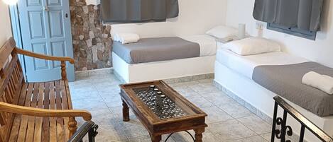A living room with a wooden bench, a glass-top coffee table, a sofa, and a white couch.