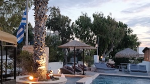 A pool area with lounge chairs, a small fountain, and a flag. - Naxos Summerland resort (Naxos)