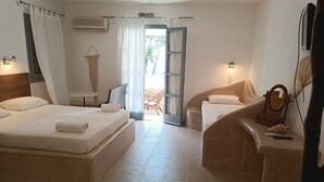 A hotel room with two beds, a sitting area with a chair and table, a small balcony, and a bathroom with a shower and toilet. - Naxos Summerland resort (Naxos)