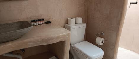 Un baño con tocador de madera, inodoro y lavamanos.