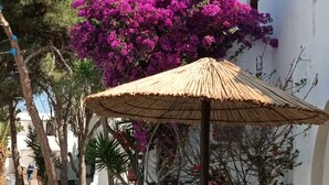 A white building with a thatched umbrella and purple bougainvillea. - Naxos Summerland resort (Naxos)