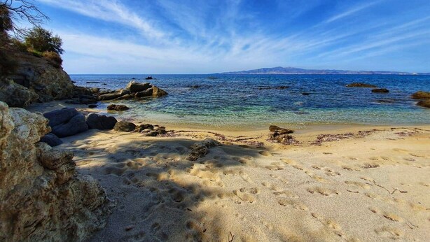 A beach with clear water, rocky formations, and a distant mountain range. - Naxos Summerland resort (Naxos)