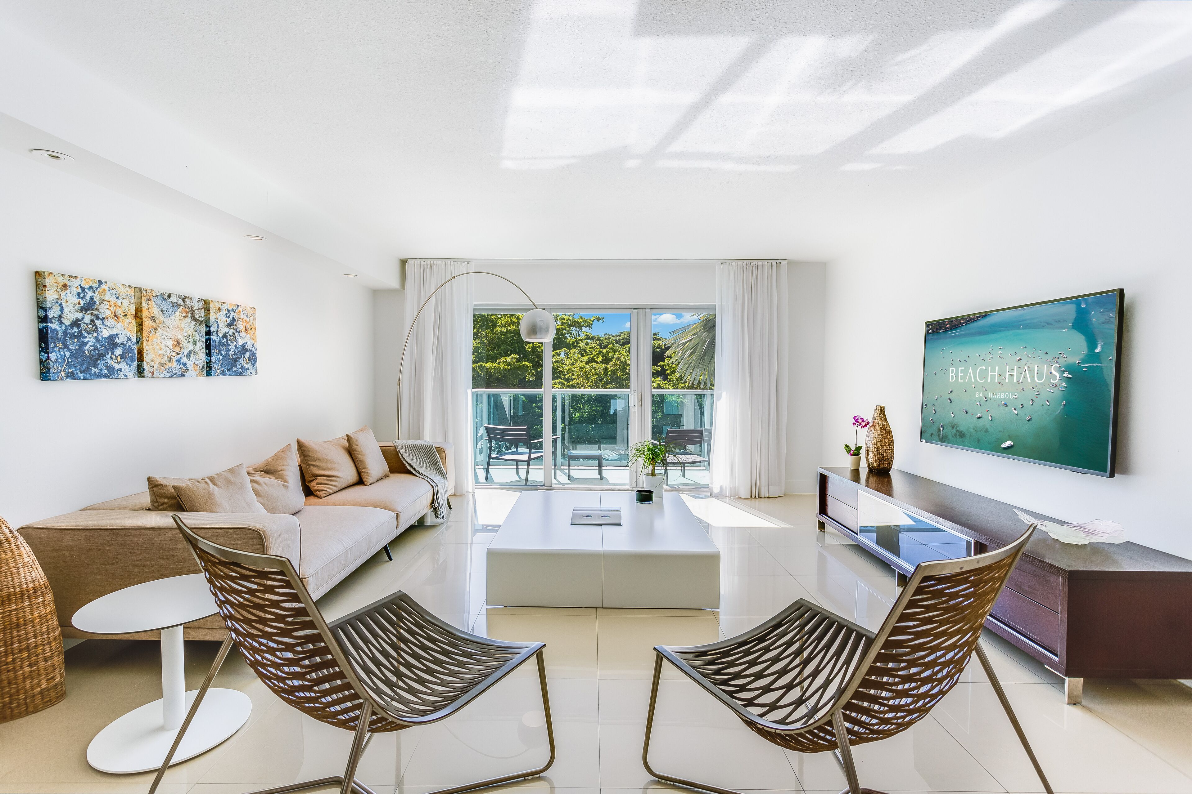 A modern living room with a sofa, two chairs, a coffee table, and a TV.