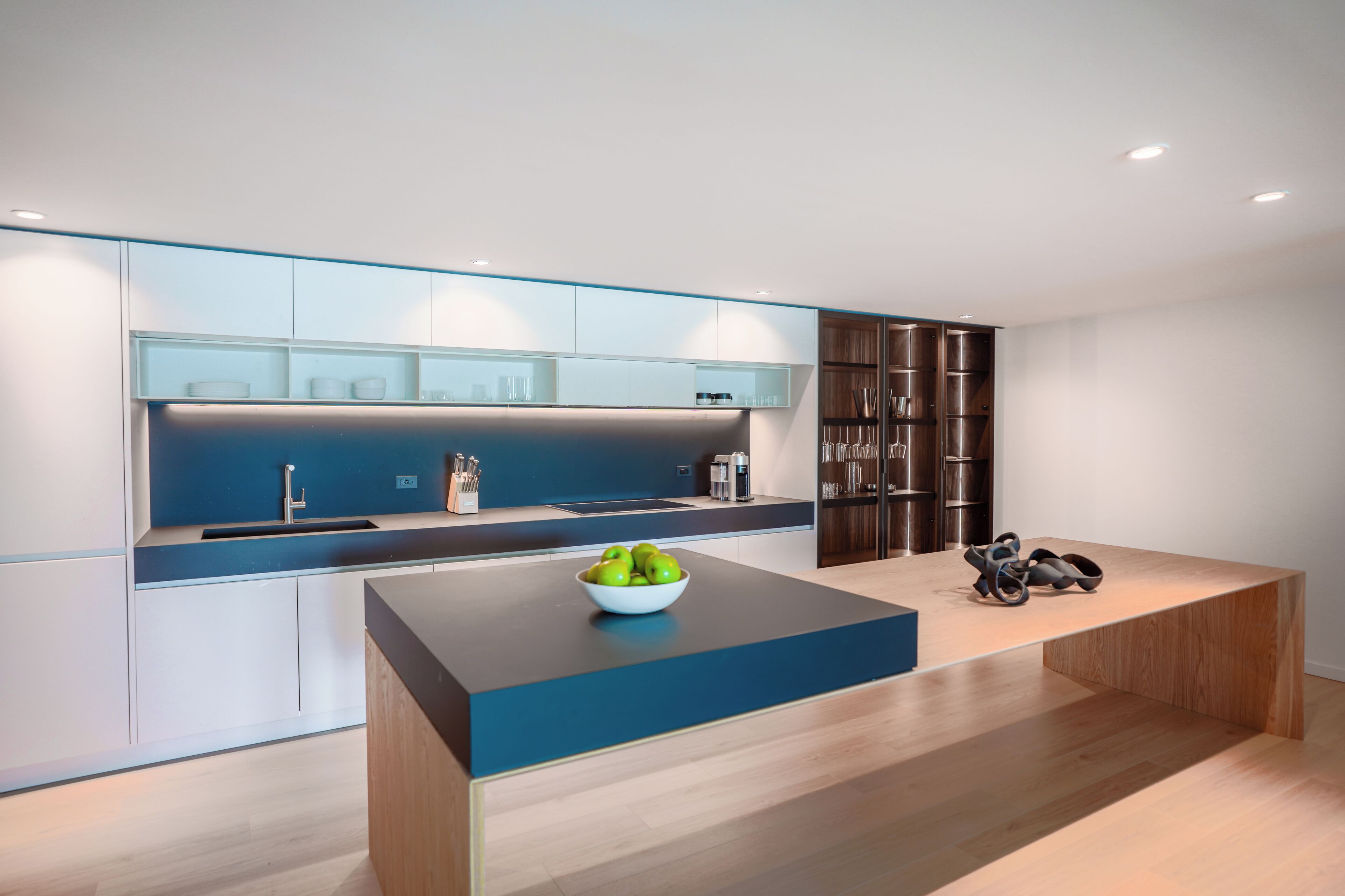 A modern kitchen with a central island, a built-in oven, and a sink.