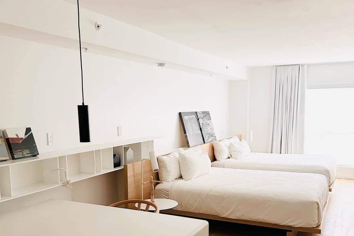 A modern hotel room with a large bed, a desk, and a chair.