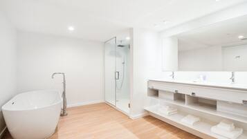 Une salle de bain moderne dotée d’une grande baignoire sur pieds, d’une douche à l’italienne et d’un meuble-lavabo avec des étagères ouvertes.