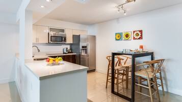 Una cocina moderna con una isla central, electrodomésticos de acero inoxidable y un comedor con sillas de madera.