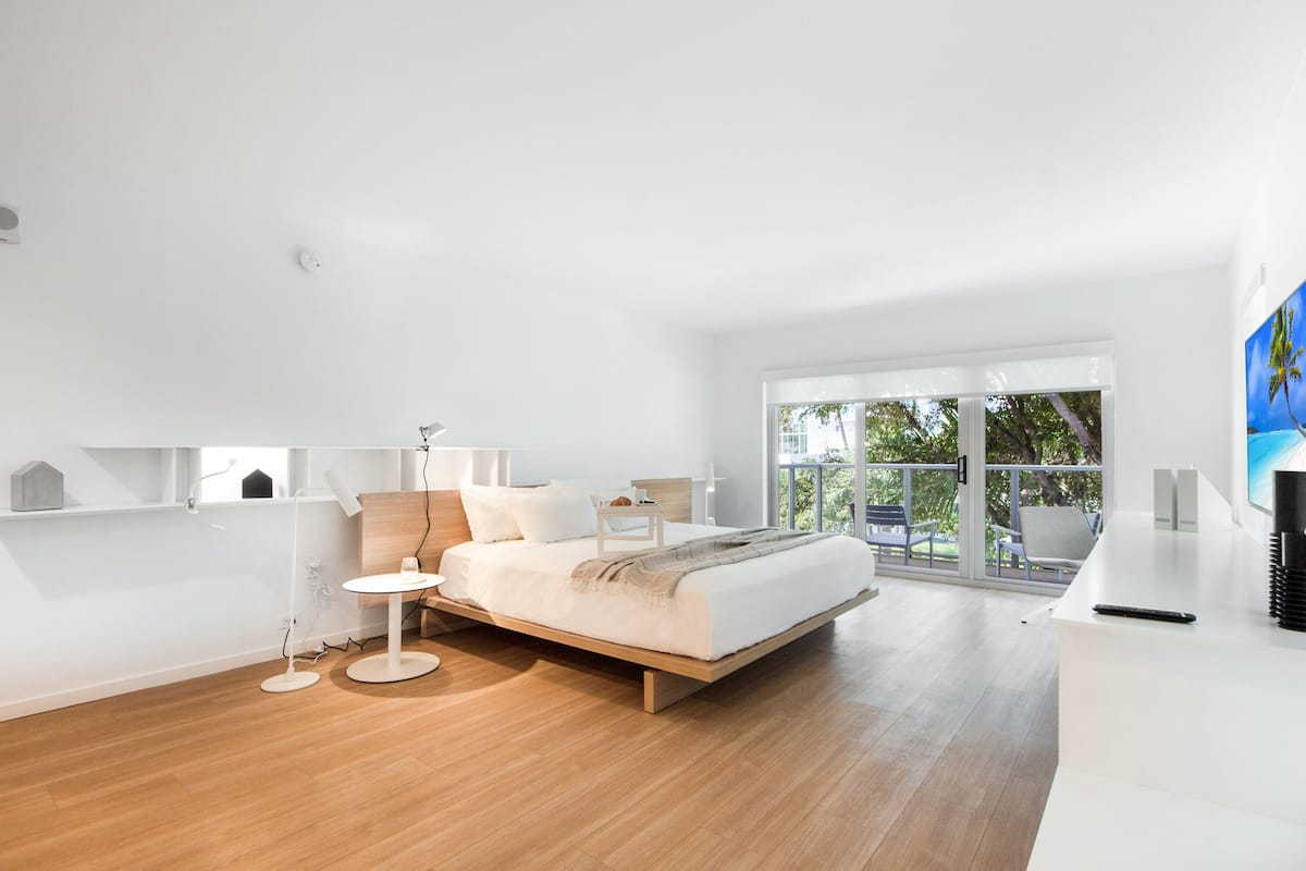 A modern bedroom with a bed, bedside tables, a lamp, and a view of the outdoors.