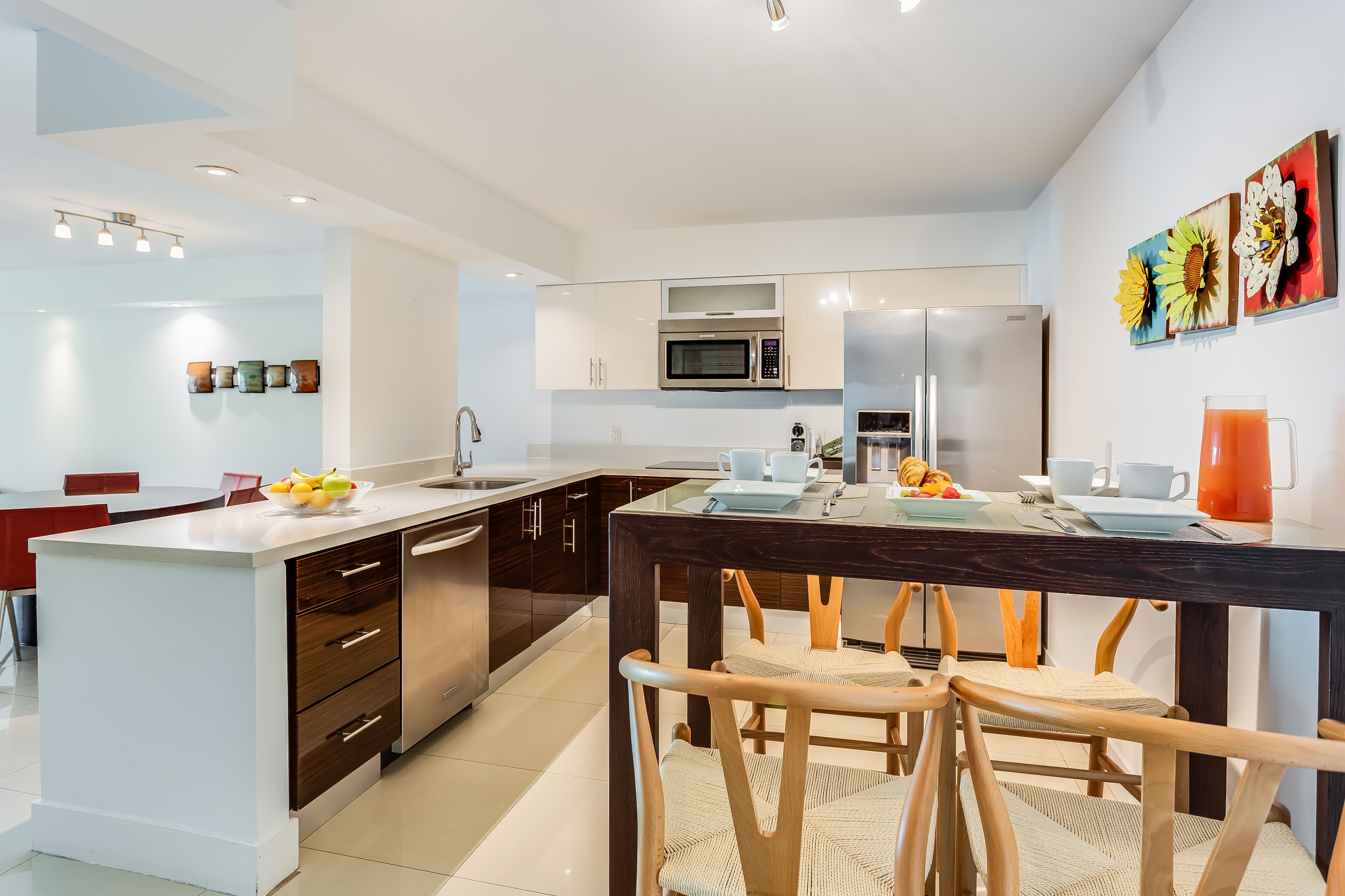 A modern kitchen with a central island, stainless steel appliances, and a dining area with wooden chairs.