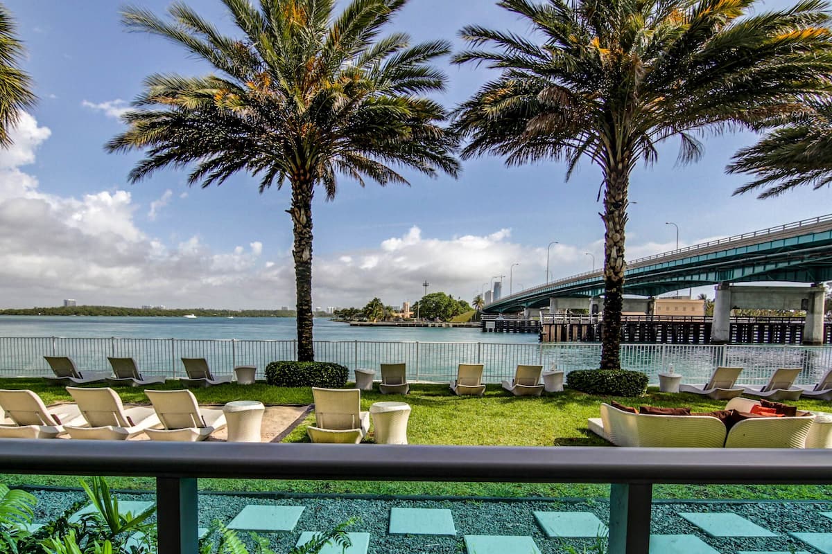 A waterfront lounge with lounge chairs and a view of the water and a bridge.