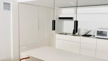 A modern kitchen with white cabinetry, a central island, two wooden chairs, and pendant lighting.