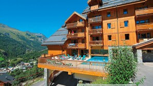 A wooden multi-story hotel with balconies and a swimming pool.