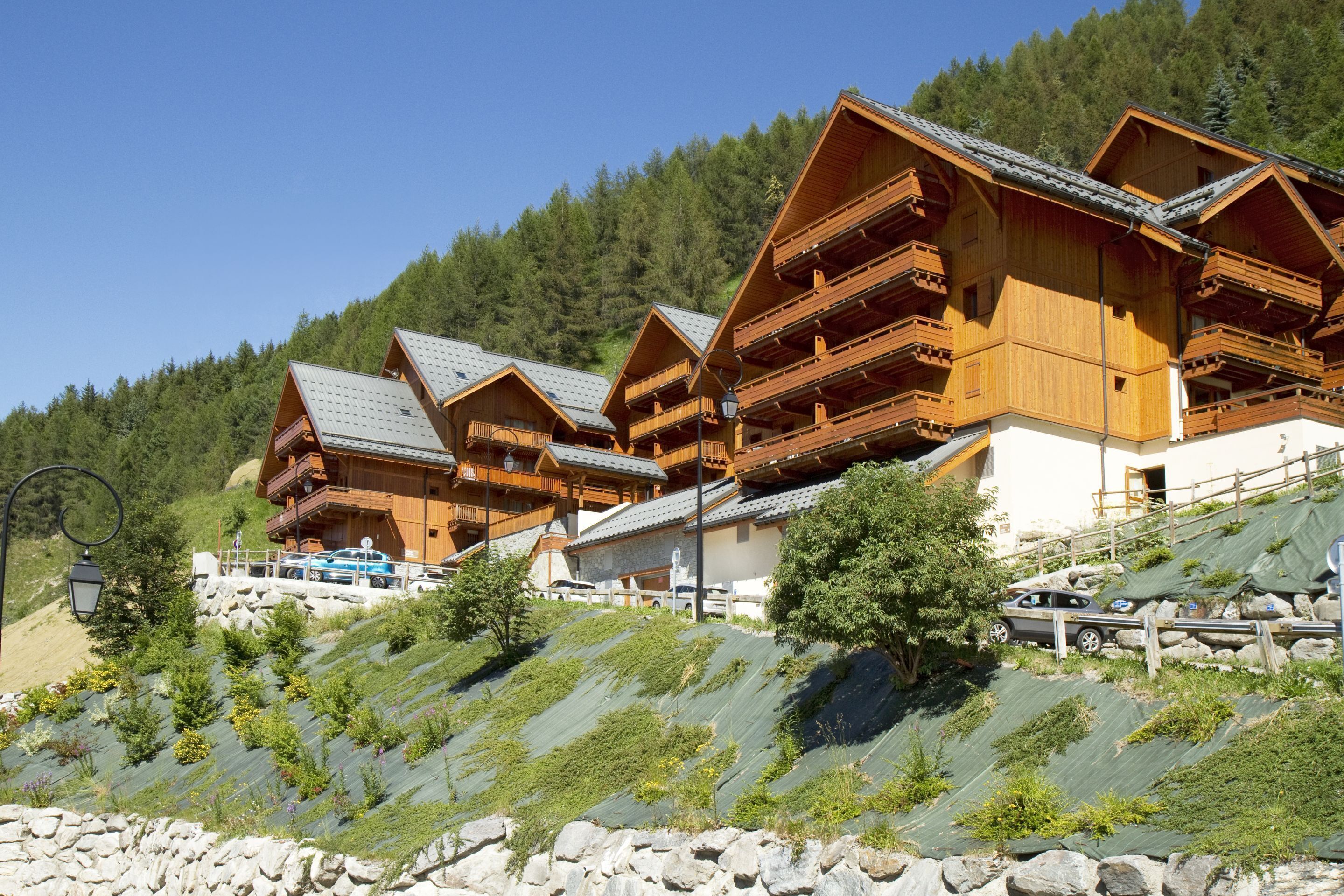 Filetta di chalet in legno con balconi, con montagne sullo sfondo.
