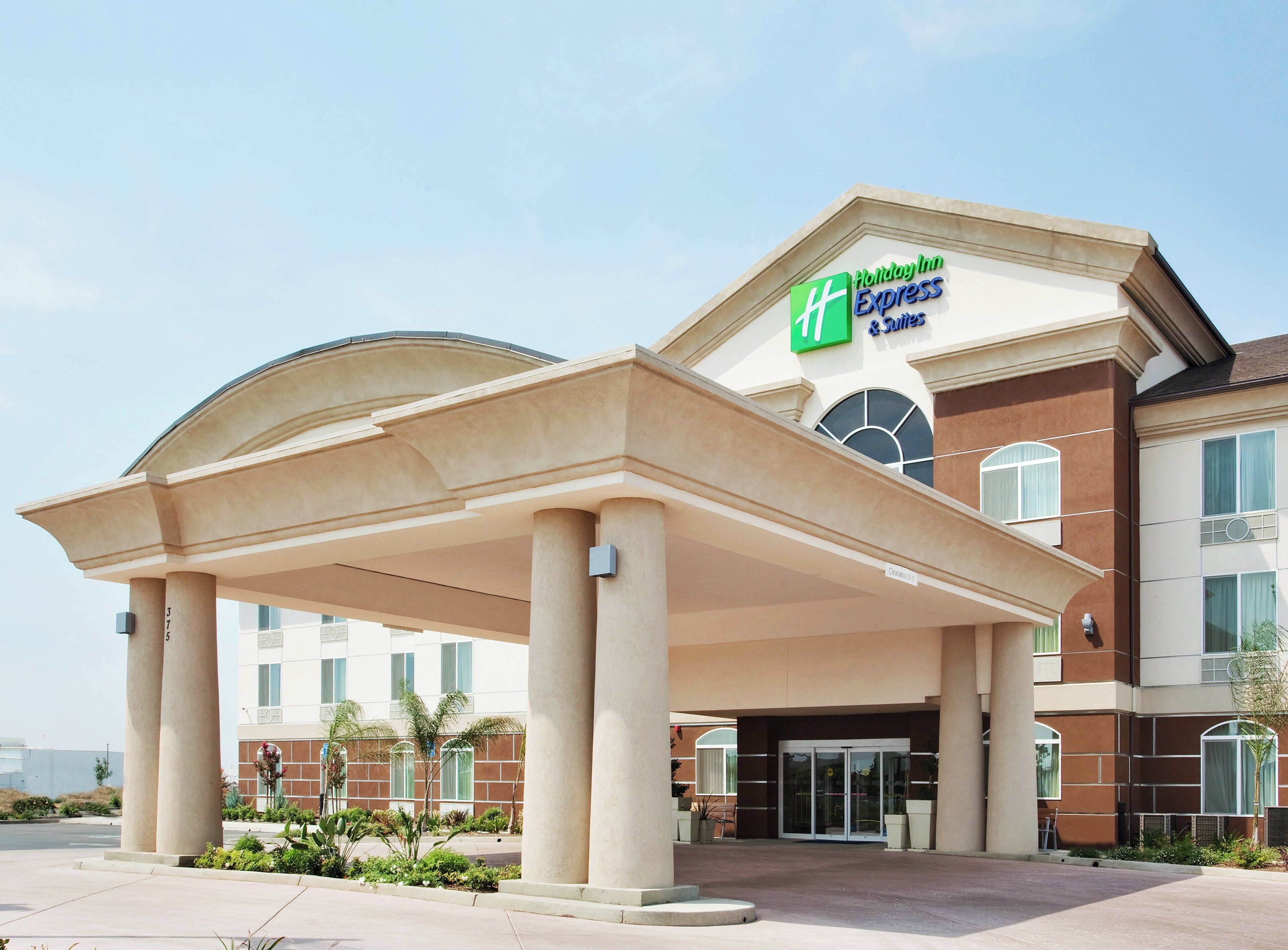 A Holiday Inn Express hotel with a covered entrance, a brick facade, and a clear sky.