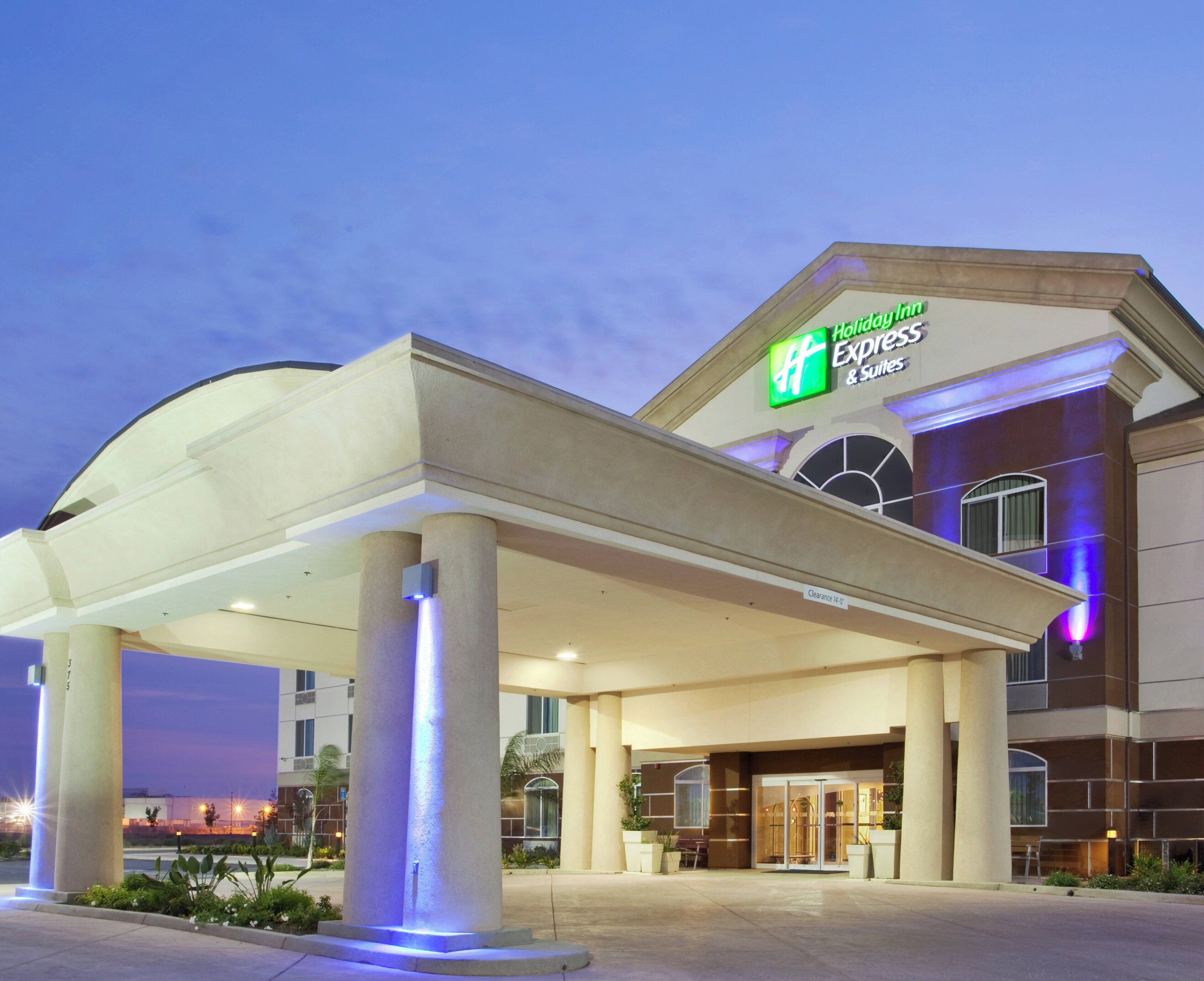 A Holiday Inn Express & Suites hotel entrance with a covered outdoor area and a clear sky.