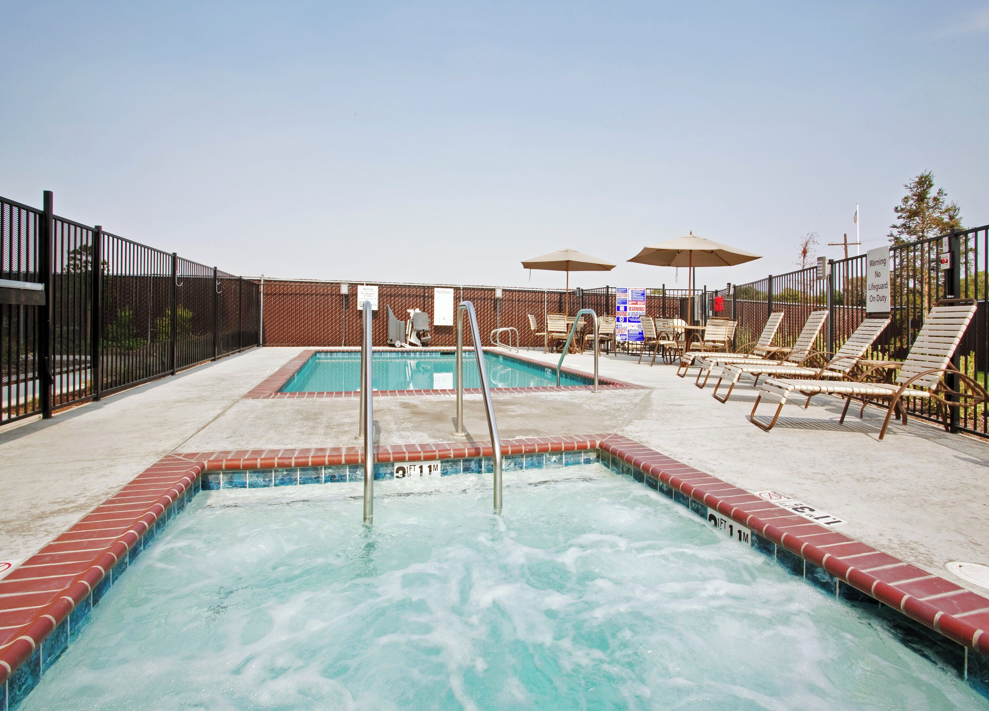 A swimming pool with a lifeguard stand, lounge chairs, and umbrellas.