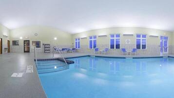 Piscina interior con carriles delimitados, vestuario y zona de estar con sillas.