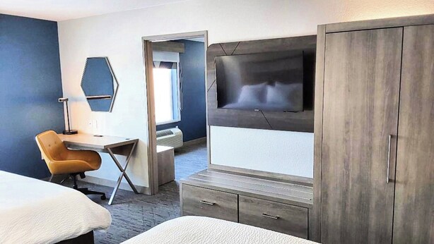 Hotellihuone, jossa on sänky, työpöytä tuolilla, televisio ja vaatekaappi.